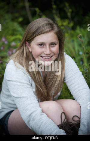 Une jeune fille avec des cheveux brune assise dans un jardin en Angleterre Banque D'Images