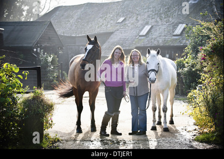 Deux femmes d'une stable avec deux chevaux d'Angleterre Banque D'Images