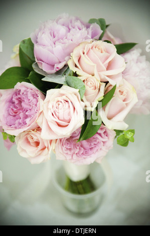 Un bouquet de roses rose pastel et lavande pâle de pivoines avec petites feuilles vertes en Angleterre
