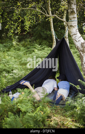 Deux garçons en camping dans la nouvelle forêt couché sous un abri de toile Hampshire Angleterre Banque D'Images