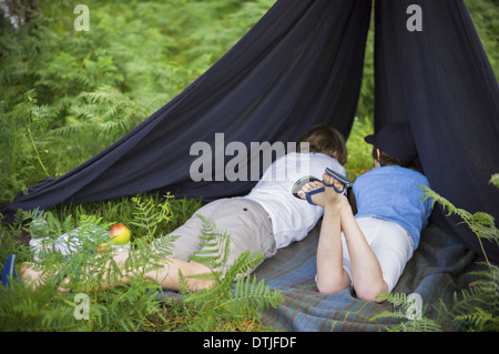Deux garçons en camping dans la nouvelle forêt couché sous un abri de toile Hampshire Angleterre Banque D'Images