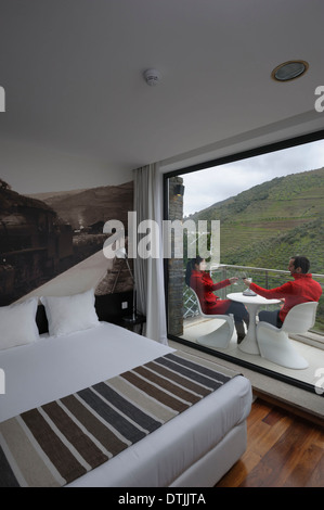 Jeune couple assis sur un balcon de boire un verre de vin Banque D'Images