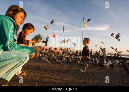 Mère et fille se nourrir les pigeons près du lac Tonlé Sap. Phnom Penh. Peuple Khmer sont le groupe ethnique dominant au Cambodge Banque D'Images