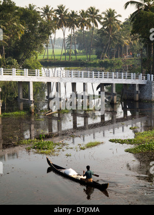 L'Inde, le Kerala, l'eau dormante, l'homme en canot en bois traditionnel qui passe sous un pont moderne en béton Banque D'Images