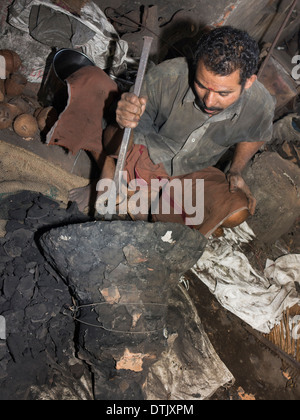 L'Inde, le Kerala, Mannar, metal foundry worker de casser le moule de cloche en bronze coulé récemment Banque D'Images