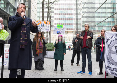 Siège social d'ATOS ORIGIN, London, UK, 19 février 2014. Comédien et activiste Mark Thomas parle à l'extérieur du siège social d'ATOS ORIGIN à Londres pour protester contre la mise en œuvre des travaux d'évaluation des capacités. Mobilité l'interprète et comédien Mat Fraser (deuxième à droite) à l'écoute de la foule. Les activistes ont appelé à l'abolition de l'évaluation de la capacité de travail et a déclaré qu'un médecin qualifié, idéalement le GP qui voit régulièrement et traite la personne malade ou handicapée en question, est la seule personne capable de décider si une personne est apte au travail. Credit : Patricia Phillips/Alamy Live News Banque D'Images