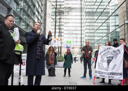 Siège social d'ATOS ORIGIN, London, UK, 19 février 2014. Comédien et activiste Mark Thomas parle à l'extérieur du siège social d'ATOS ORIGIN à Londres pour protester contre la mise en œuvre des travaux d'évaluation des capacités. Mobilité l'interprète et comédien Mat Fraser (cinquième à partir de la droite) à l'écoute de la foule. Les activistes ont appelé à l'abolition de l'évaluation de la capacité de travail et a déclaré qu'un médecin qualifié, idéalement le GP qui voit régulièrement et traite la personne malade ou handicapée en question, est la seule personne capable de décider si une personne est apte au travail. Credit : Patricia Phillips/Alamy Live News Banque D'Images