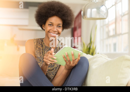 Woman using digital tablet on sofa Banque D'Images