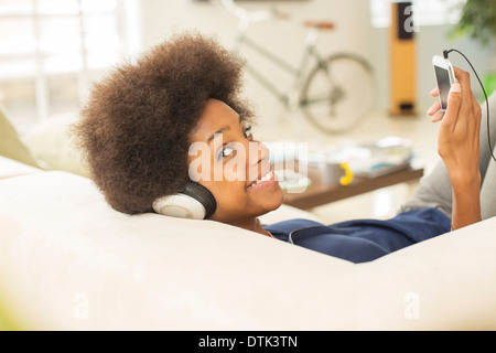 Woman listening to headphones on sofa Banque D'Images