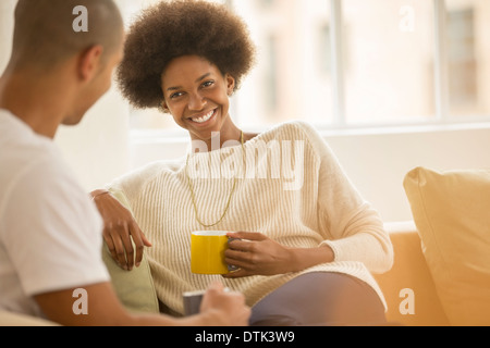 Couple drinking coffee sur canapé Banque D'Images