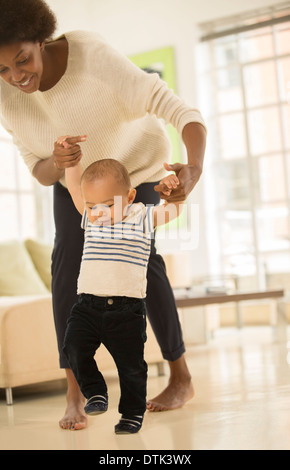 Mother helping baby boy à pied dans la salle de séjour Banque D'Images