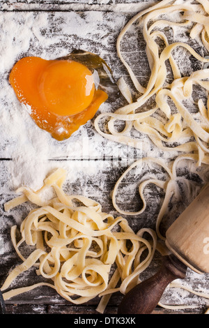 Vue de dessus sur les matières des pâtes avec de la farine, du sel de mer et d'oeuf cru comme coeur sur table en bois ancien Banque D'Images