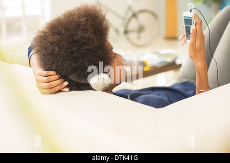 Woman listening to headphones on sofa Banque D'Images