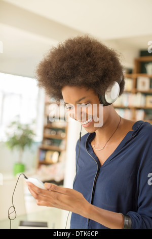 Woman listening to headphones in living room Banque D'Images