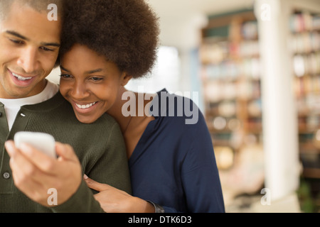 Couple using cell phone in living room Banque D'Images