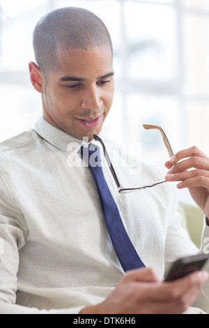 Businessman using cell phone on sofa Banque D'Images