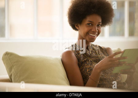 Woman using digital tablet on sofa Banque D'Images