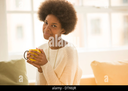 Femme buvant du café sur canapé Banque D'Images