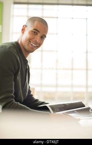 Smiling man reading magazine Banque D'Images