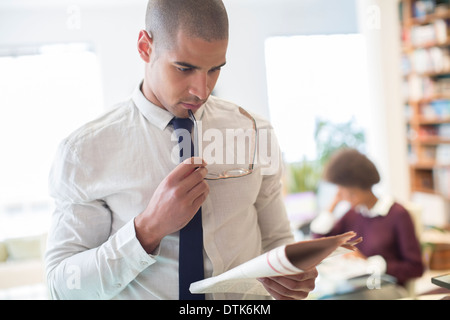 Businessman reading newspaper in living room Banque D'Images