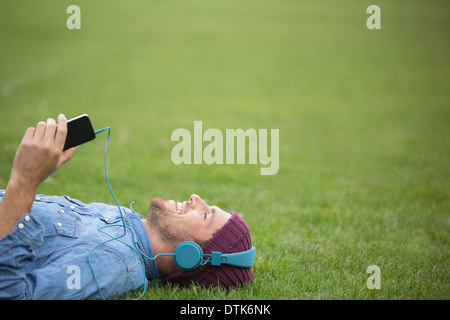 Man listening to headphones on lawn Banque D'Images