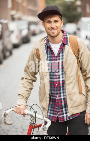 Man pushing bicycle on city street Banque D'Images