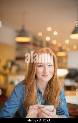 Woman using cell phone in cafe Banque D'Images