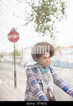 Woman riding bicycle on city street Banque D'Images