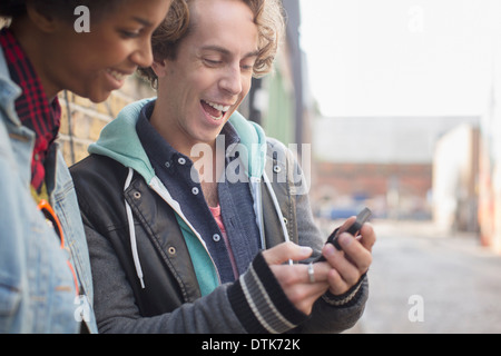 Couple using cell phone on city street Banque D'Images