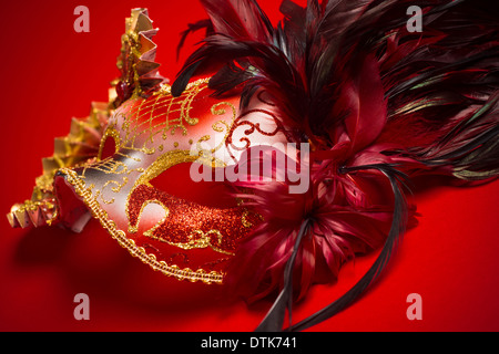 Un rouge, or et noir mardi gras ou masque de Venise sur un fond rouge Banque D'Images