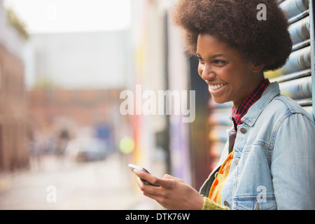 Woman using cell phone on city street Banque D'Images