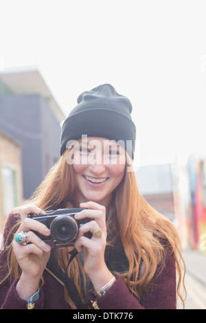 Femme à l'aide d'appareil photo on city street Banque D'Images