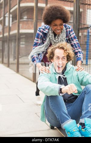 Couple playing on skateboard on city street Banque D'Images