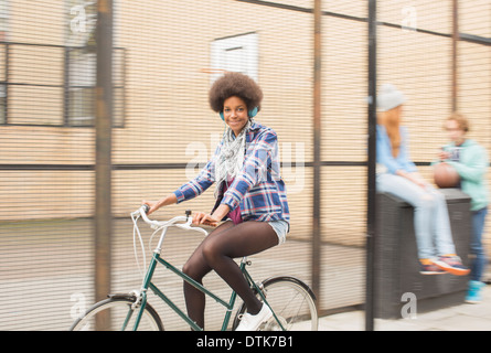 Woman riding bicycle on city street Banque D'Images