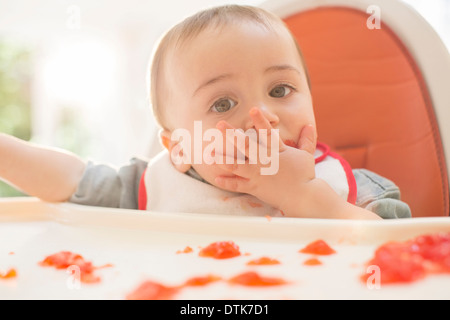 Baby Boy eating dessert la gélatine dans une chaise haute Banque D'Images