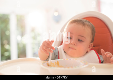 Baby Boy de manger dans une chaise haute Banque D'Images