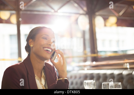 Businesswoman talking on cell phone in restaurant Banque D'Images