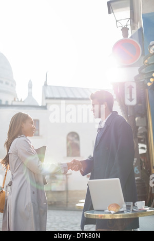 Business people shaking hands at sidewalk cafe, Paris, France Banque D'Images