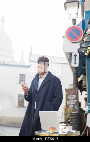 Businessman using cell phone at sidewalk cafe Banque D'Images