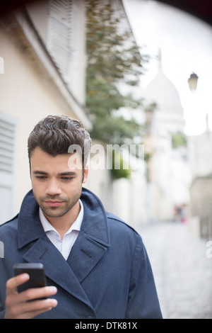 Businessman using cell phone on city street Banque D'Images