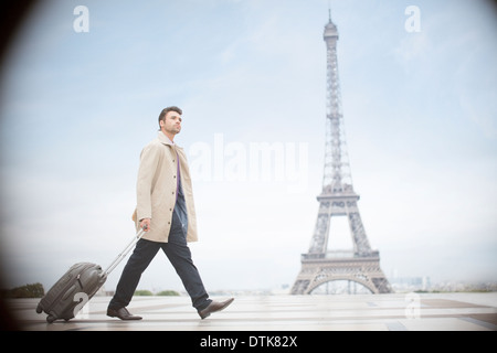 Businessman pulling suitcase près de Eiffel Tower, Paris, France Banque D'Images