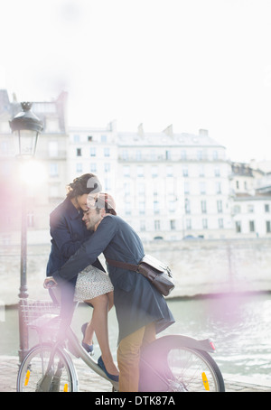 Couple hugging on à vélo le long de la rivière Seine, Paris, France Banque D'Images