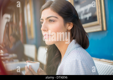 Woman drinking espresso at sidewalk cafe Banque D'Images