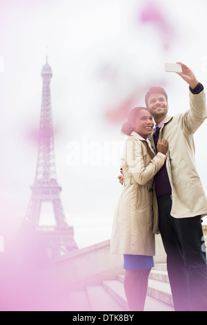 Couple taking self-portrait en face de la Tour Eiffel, Paris, France Banque D'Images