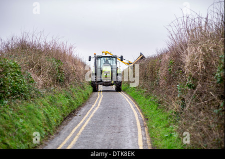 Un tracteur est utilisé pour couper une haie sur un étroit chemin de campagne dans le sud du Pays de Galles, Royaume-Uni. Banque D'Images