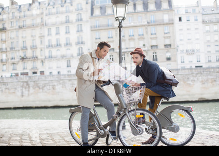 Les hommes sur les bicyclettes reading map le long de la rivière Seine, Paris, France Banque D'Images