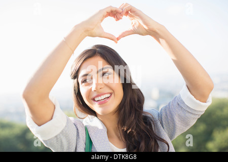 Woman making heart-shape avec hands outdoors Banque D'Images