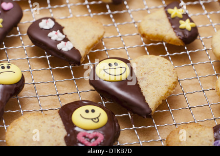 Prêt-petits gâteaux en forme de coeur avec un décor de chocolat et le sucre en plan rapproché sur un rack de gâteau Banque D'Images