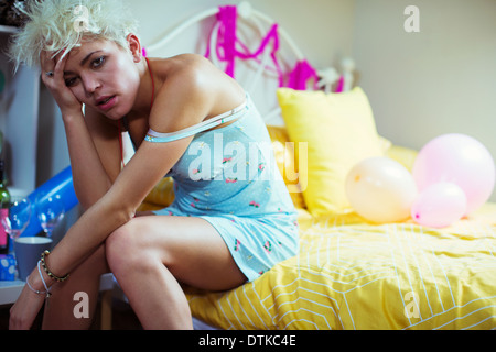 Gueule de femme assise sur le lit le matin après une fête Banque D'Images