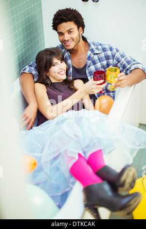 Couple toasting each other in bathtub at party Banque D'Images